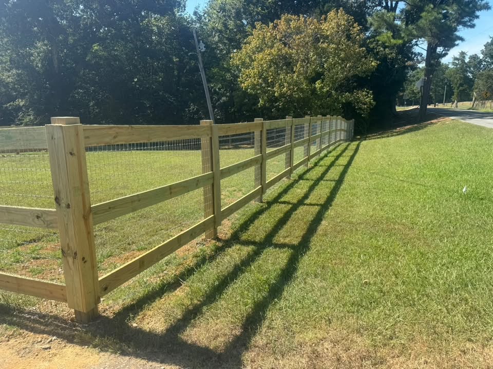 Wooden rail fence with wire mesh built by Integrity Fence & Outdoor along a country road